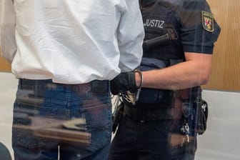 Ein Justizbediensteter überprüft im Landgericht Trier die Handfesseln des Angeklagten.