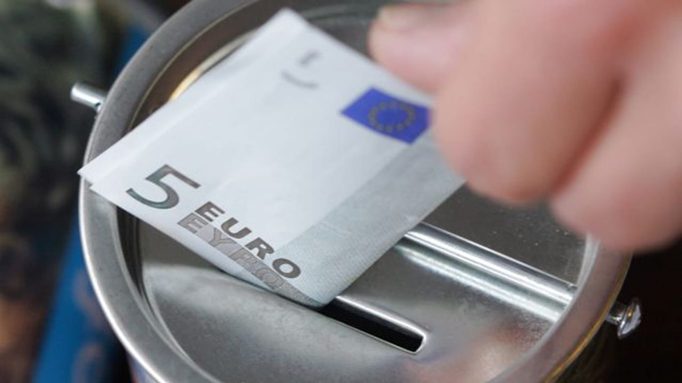 Ein Fünf-Euro-Schein wird in eine Spendendose gesteckt.