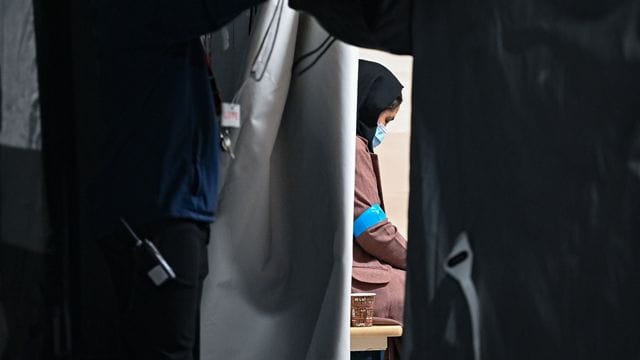 Eine Frau, die zusammen mit weiteren Ortskräften aus Afghanistan am frühen Morgen auf dem Gelände der DRK-Flüchtlingshilfe. Eine Frau, die zusammen mit weiteren Ortskräften aus Afghanistan am frühen Morgen auf dem Gelände der DRK-Flüchtlingshilfe.