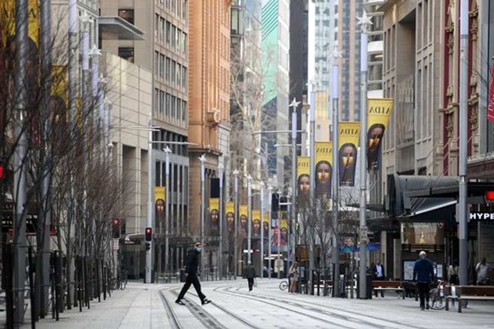 Passanten gehen über eine fast menschenleere Straße im Geschäfts- und Einkaufsviertel von Sydney.