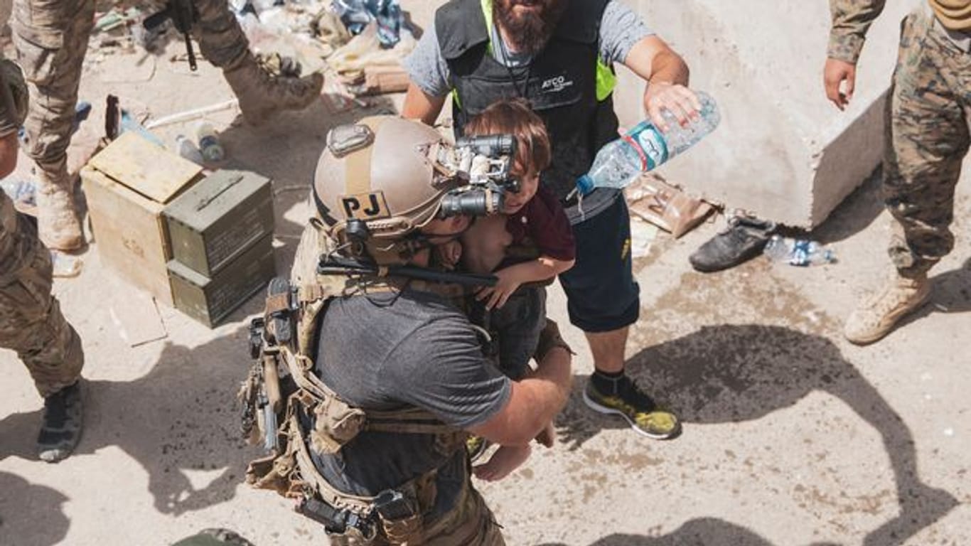 Auf diesem vom US Marine Corps zur Verfügung gestellten Foto trägt ein US-Soldat ein Kind an einem Evakuierungskontrollpunkt am Kabuler Flughafen.