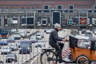 Ein Lastenrad-Fahrer fährt über eine Brücke über der Autobahn 7 in Hamburg.