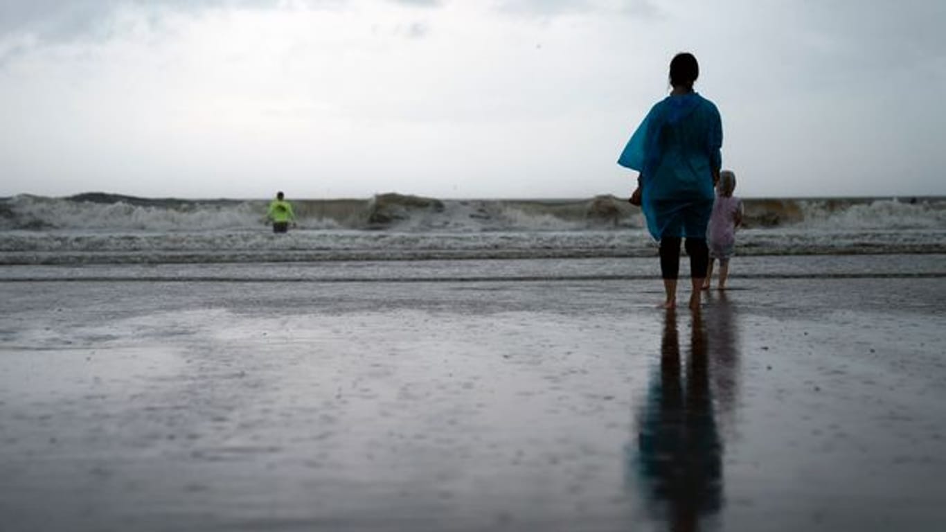 Kamila Struk (r) beobachtet ihren Vater Nickolas, der an einem gesperrten Strand in die Wellen watet, während der Tropensturm "Henri" über den US-Bundesstaat New York zieht.