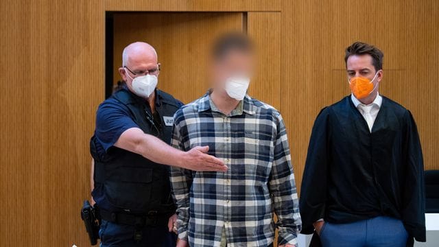 Einer der beiden wegen Mordes angeklagten Männer (M) wird in den Sitzungssaal geführt. Einer der beiden wegen Mordes angeklagten Männer (M) wird in den Sitzungssaal geführt.