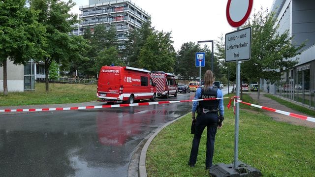 Eine Beamtin und Einsatzfahrzeuge der Feuerwehr auf dem Campus der TU Darmstadt.