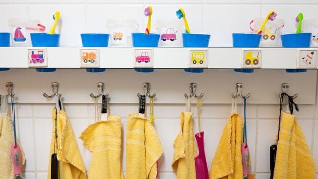 Handtücher und Zahnputzbecher hängen und stehen in einer Kindertagesstätte im Waschraum. Handtücher und Zahnputzbecher hängen und stehen in einer Kindertagesstätte im Waschraum.