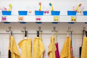 Handtücher und Zahnputzbecher hängen und stehen in einer Kindertagesstätte im Waschraum.