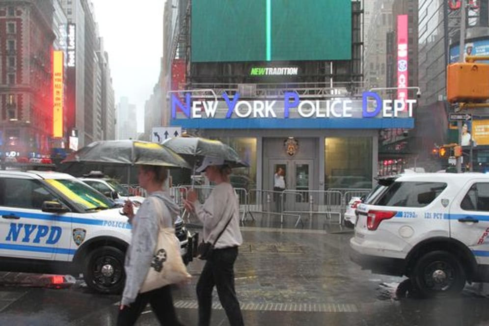 Fußgängerinnen mit Regenschirmen am Times Square in New York.