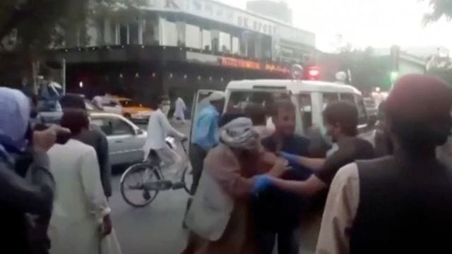 Menschen kümmern sich um eine verwundete Person in der Nähe der Explosion außerhalb des Flughafens in Kabul. Menschen kümmern sich um eine verwundete Person in der Nähe der Explosion außerhalb des Flughafens in Kabul.
