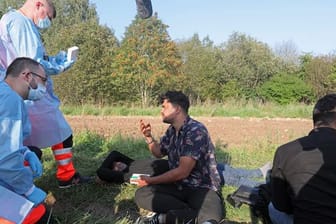Sanitäter sprechen mit der Gruppe von Flüchtlingen an der polnisch-belarussischen Grenze.