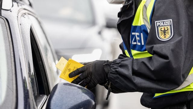 Ein deutscher Bundespolizist kontrolliert an der Grenze zu Österreich den Impfpass einer einreisenden Person. Ein deutscher Bundespolizist kontrolliert an der Grenze zu Österreich den Impfpass einer einreisenden Person.