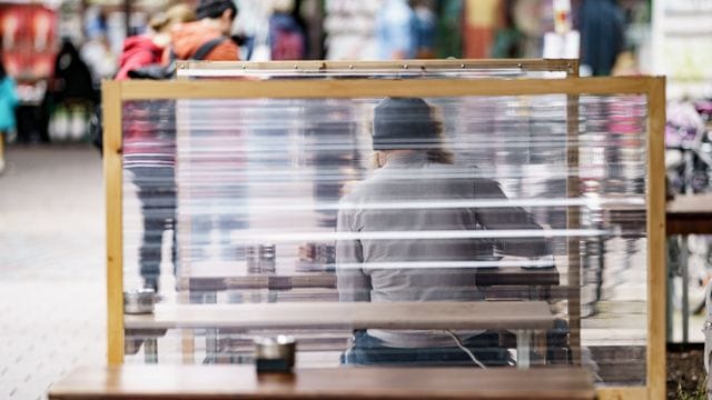 Gäste eines Restaurants warten zwischen Plexiglas-Trennscheiben auf ihre Bestellung. Gäste eines Restaurants warten zwischen Plexiglas-Trennscheiben auf ihre Bestellung.