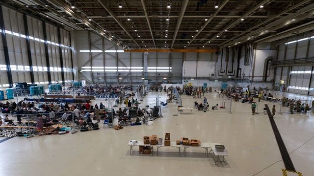 Für die Abfertigung von Passagieren, die zu ihrem nächsten Ziel transportiert werden sollen, wurde ein Wartungshangar in einen kleinen internationalen Flughafen umgewandelt. Für die Abfertigung von Passagieren, die zu ihrem nächsten Ziel transportiert werden sollen, wurde ein Wartungshangar in einen kleinen internationalen Flughafen umgewandelt.