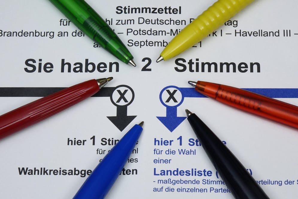 Stimmzettel zur Bundestagswahl und Kugelschreiber in den Parteifarben