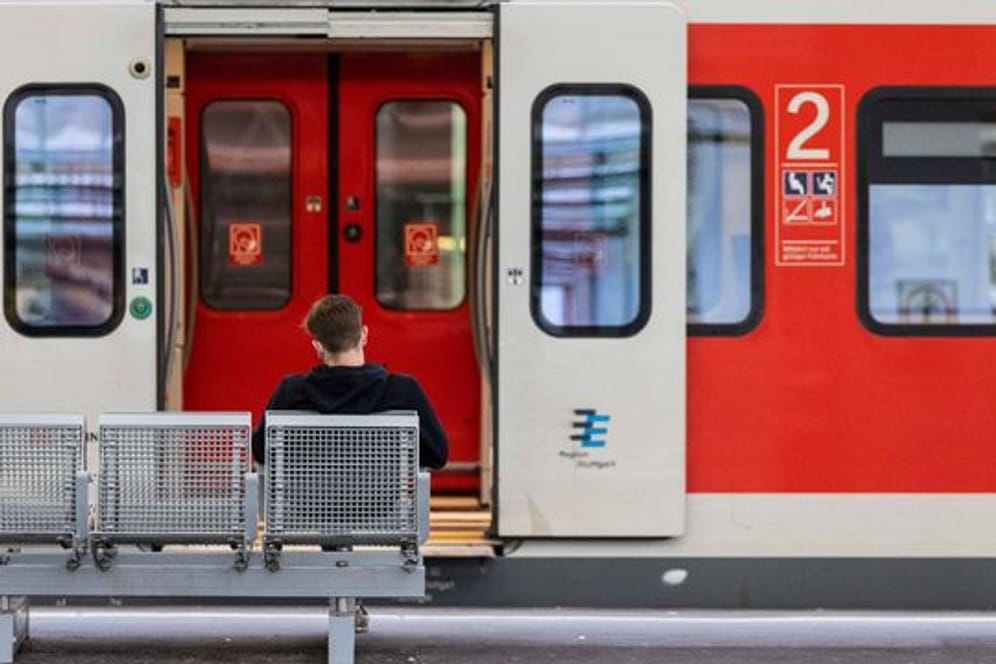 Ein Mann sitzt an einem Bahnhof vor einem Zug