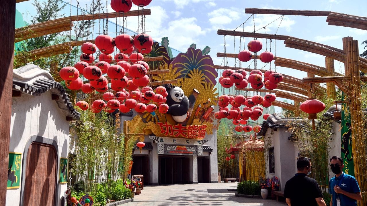 Männer mit Mund-Nasen-Schutz stehen im Inneren des Vergnügungsparks von Universal Studios. Männer mit Mund-Nasen-Schutz stehen im Inneren des Vergnügungsparks von Universal Studios.