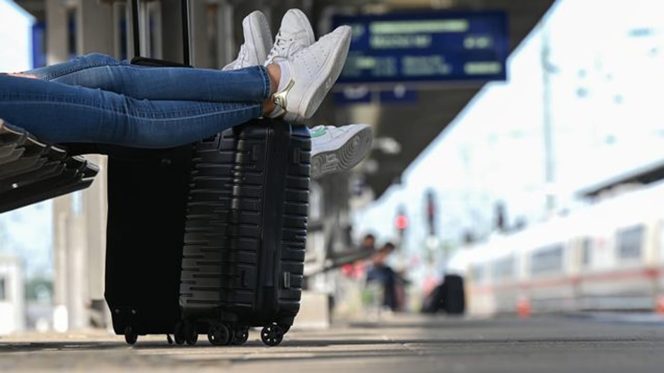 Zwei Reisegäste warten an einem Bahnhof am Gleis