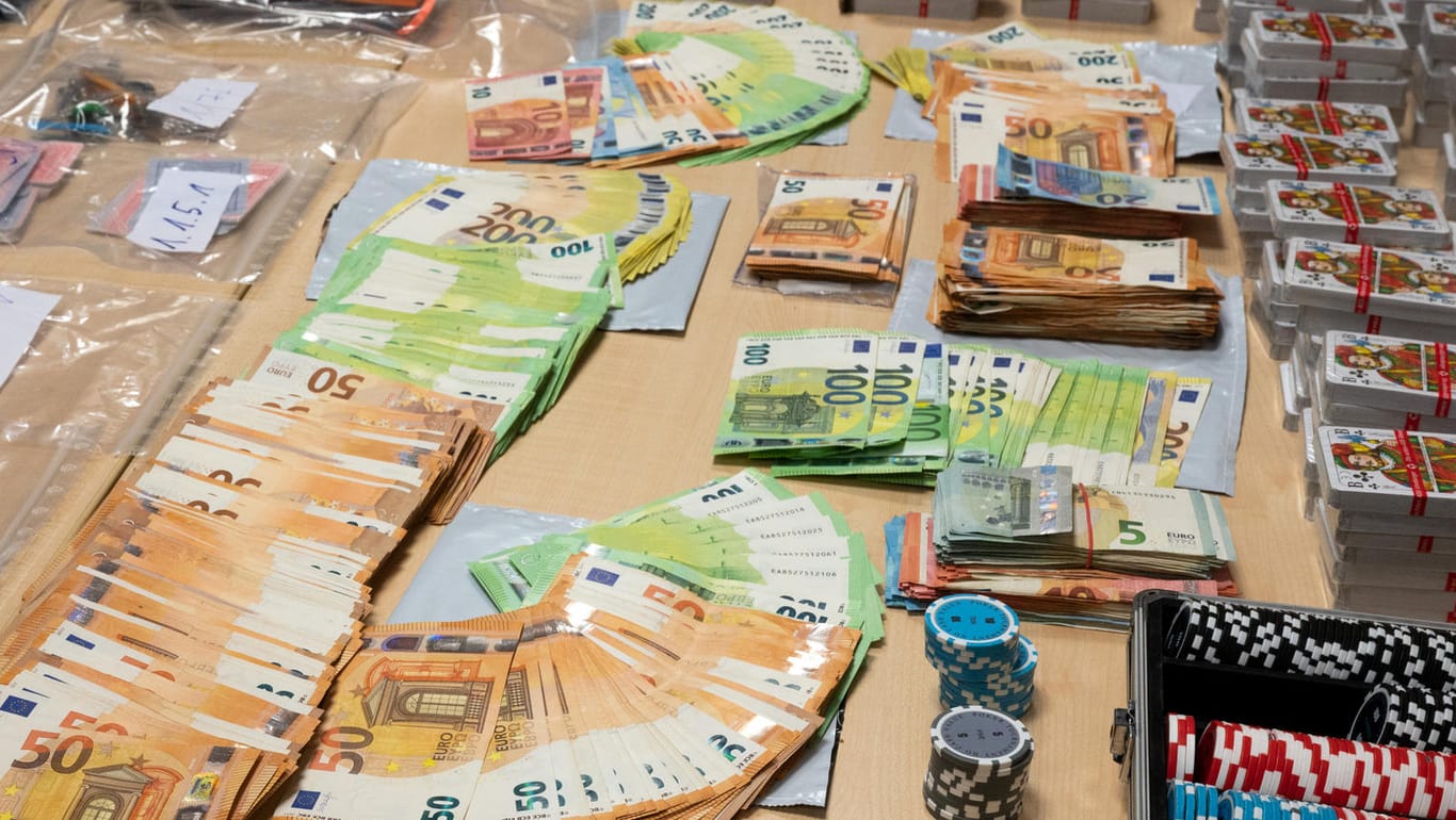 Geldscheine und Spielkarten liegen bei der Polizei auf einem Tisch: Bei der Razzia wurden wurden rund 90.000 Euro beschlagnahmt.
