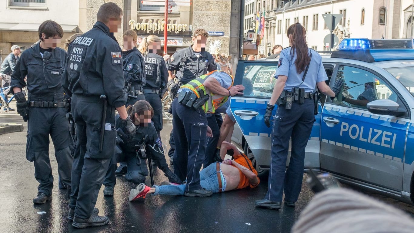 Die Szene am Polizeiwagen: Sven liegt am Boden, umringt von mehreren Polizisten.