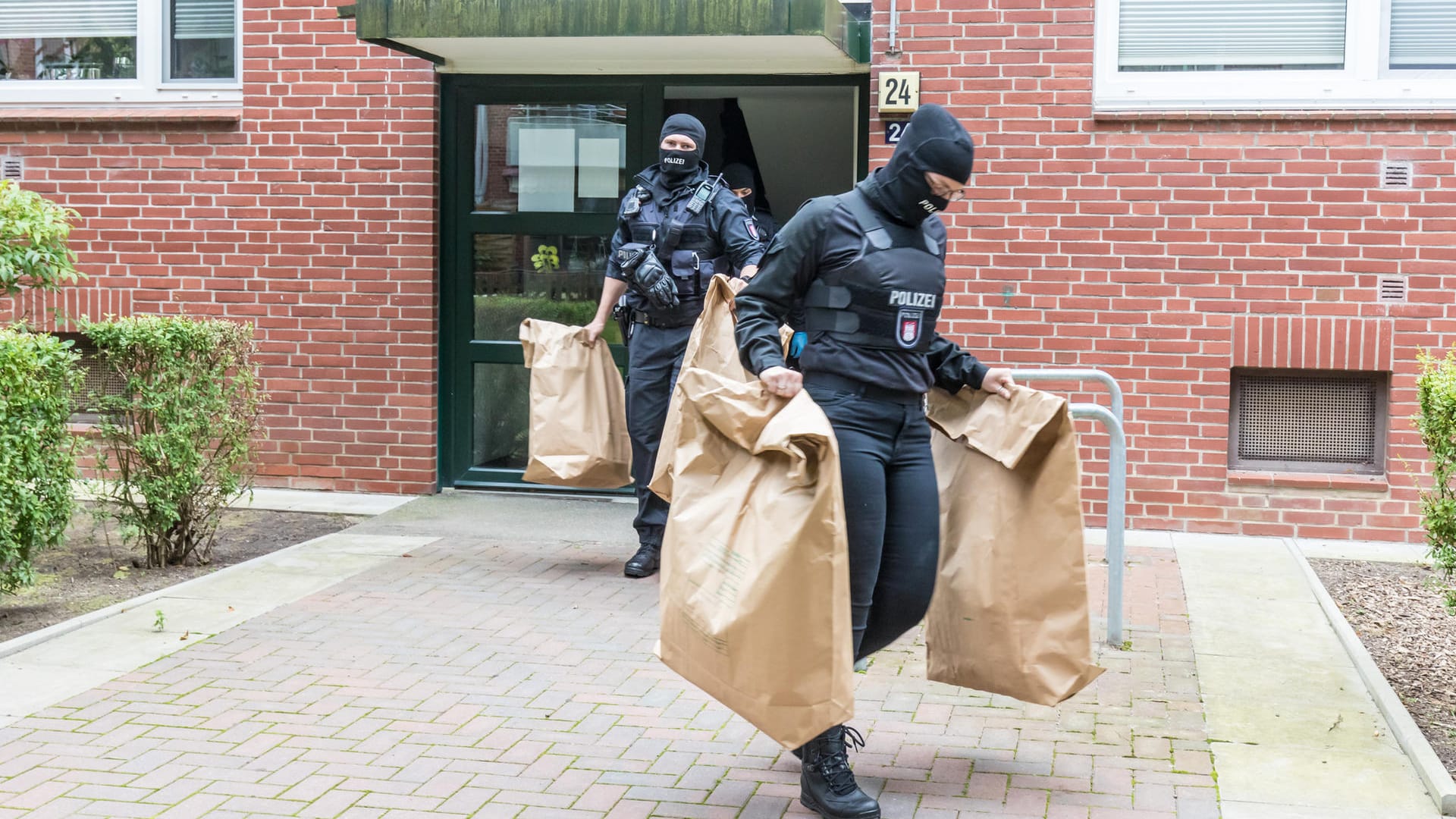 Polizeibeamte stellen bei einer Durchsuchung Gegenstände sicher: Bei der Razzia wurden auch Drogen beschlagnahmt. Polizeibeamte stellen bei einer Durchsuchung Gegenstände sicher: Bei der Razzia wurden auch Drogen beschlagnahmt.