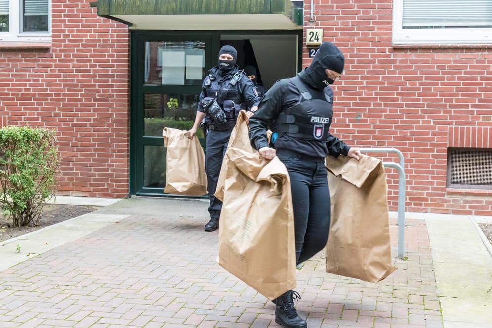 Polizeibeamte stellen bei einer Durchsuchung Gegenstände sicher: Bei der Razzia wurden auch Drogen beschlagnahmt.