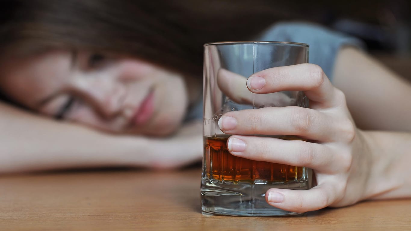 Eine Frau betrachtet ein Glas mit Whisky. Alkoholsucht kommt nicht von heute auf morgen. Der Weg in die Sucht ist fast immer ein längerer Prozess.