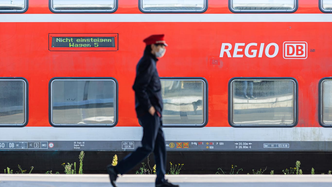 Ein Mitarbeiter der Deutschen Bahn (DB) läuft auf einem Bahnsteig und ein Zug der DB Regio steht auf einem Gleis dahinter. (Archivbild). Die GDL wird zu Verhandlungen gedrängt.