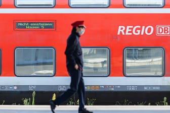 Ein Mitarbeiter der Deutschen Bahn (DB) läuft auf einem Bahnsteig und ein Zug der DB Regio steht auf einem Gleis dahinter. (Archivbild). Die GDL wird zu Verhandlungen gedrängt.