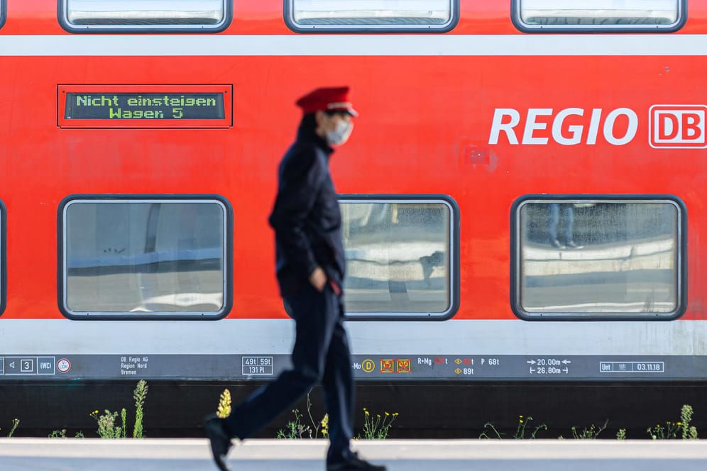 Ein Mitarbeiter der Deutschen Bahn (DB) läuft auf einem Bahnsteig und ein Zug der DB Regio steht auf einem Gleis dahinter. (Archivbild). Die GDL wird zu Verhandlungen gedrängt.