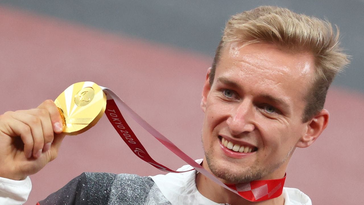 Johannes Floors hält bei der Siegerehrung seine Goldmedaille hoch.