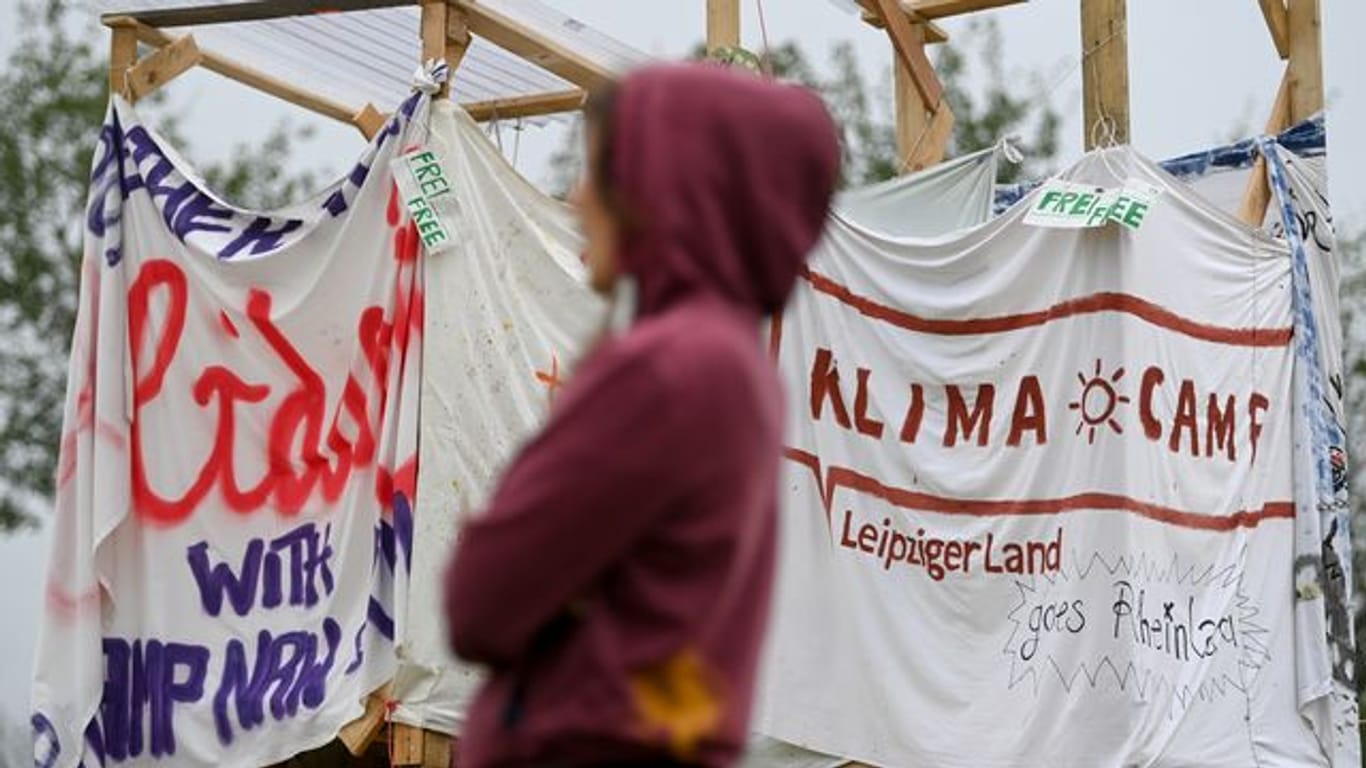 Eine Aktivistin des Klimacamps bei Leipzig steht vor Bannern