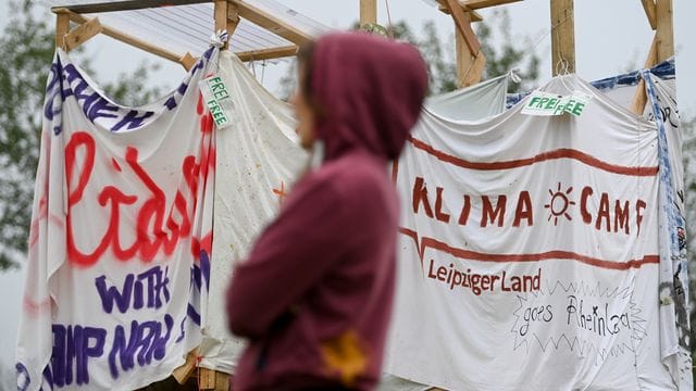 Eine Aktivistin des Klimacamps bei Leipzig steht vor Bannern Eine Aktivistin des Klimacamps bei Leipzig steht vor Bannern