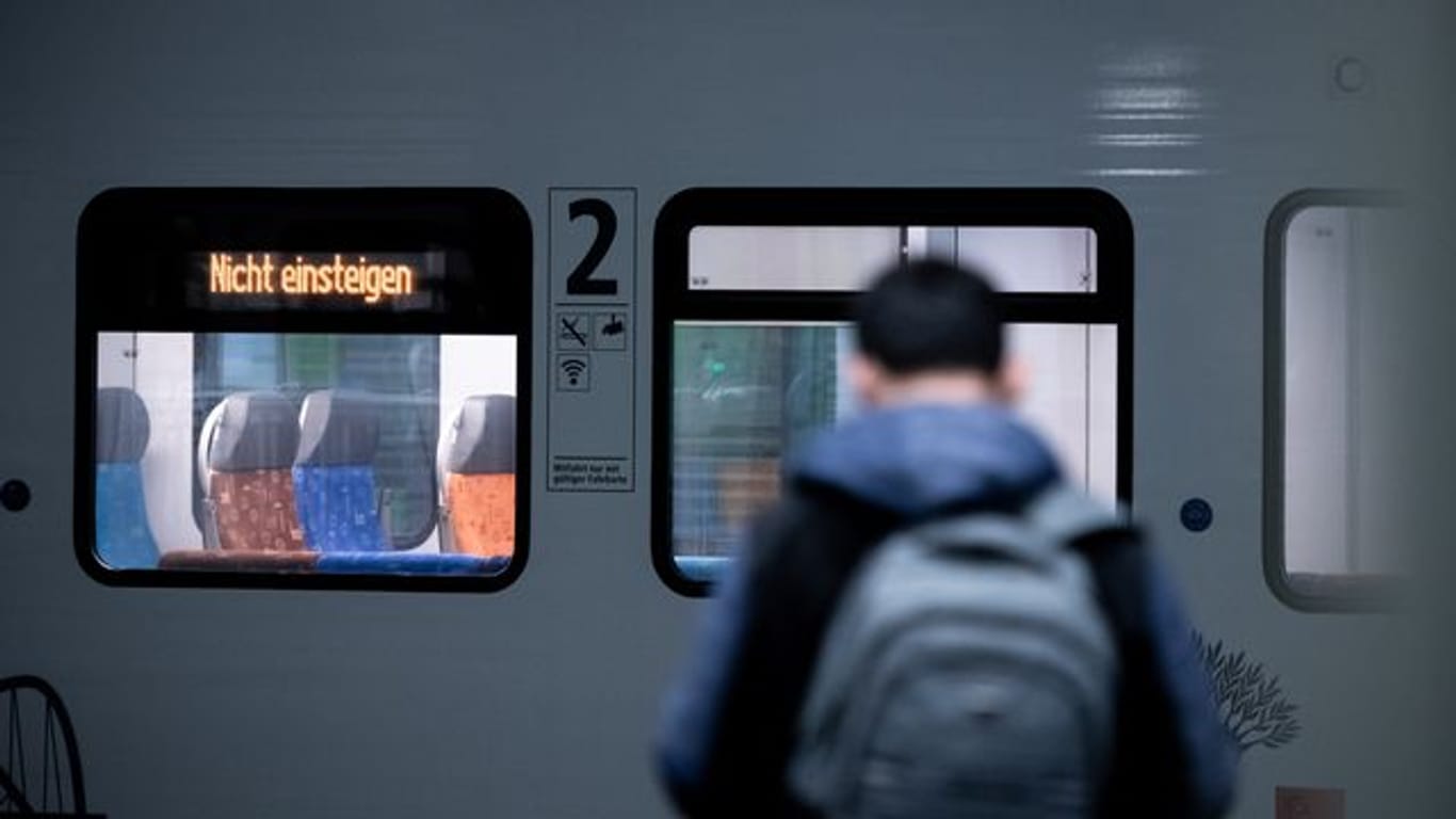 Ein Mann steht vor einem Zug, auf dem "Nicht einsteigen" steht