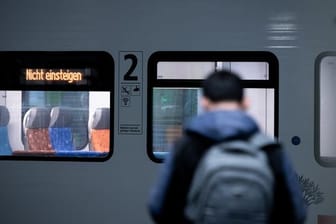 Ein Mann steht vor einem Zug, auf dem "Nicht einsteigen" steht