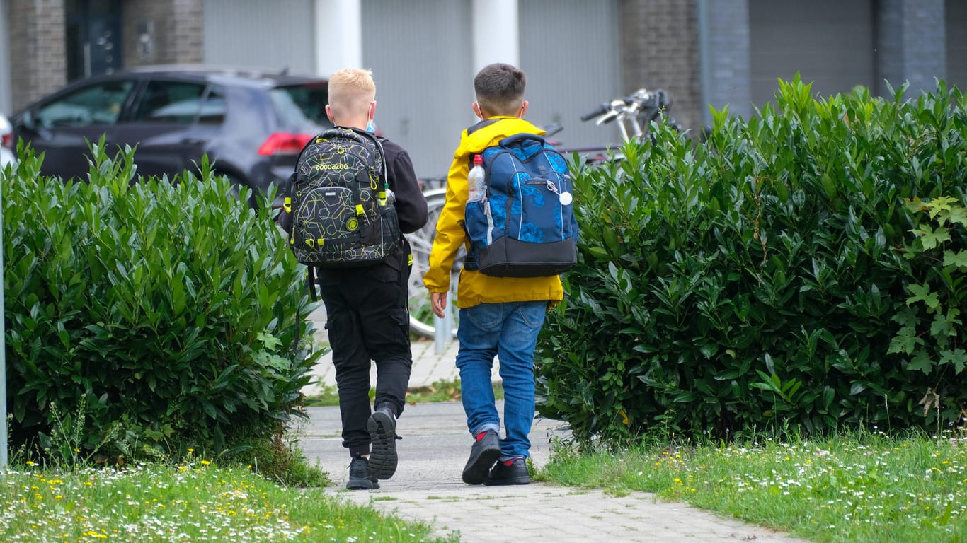Zwei Schüler laufen mit einem Tornister auf einem Weg (Symbolbild): Die Stadt Dortmund spricht sich für die Lockerung der Quarantäne unter Schülern aus.