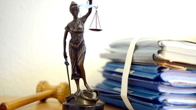 Justitia steht neben einem Holzhammer und Akten Justitia steht neben einem Holzhammer und Akten
