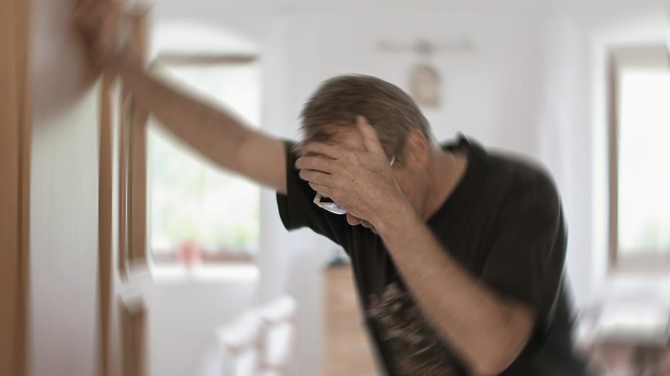 Ein Mann stützt sich im Türrahmen ab: Neben anderen Symptomen kann sich ein Schlaganfall durch Schwindel äußern.