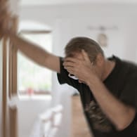 Ein Mann stützt sich im Türrahmen ab: Neben anderen Symptomen kann sich ein Schlaganfall durch Schwindel äußern.
