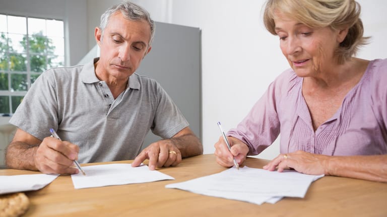 Ein Mann und eine Frau unterzeichnen einen Vertrag: Über einen privaten Darlehensvertrag können Sie sich Geld leihen.