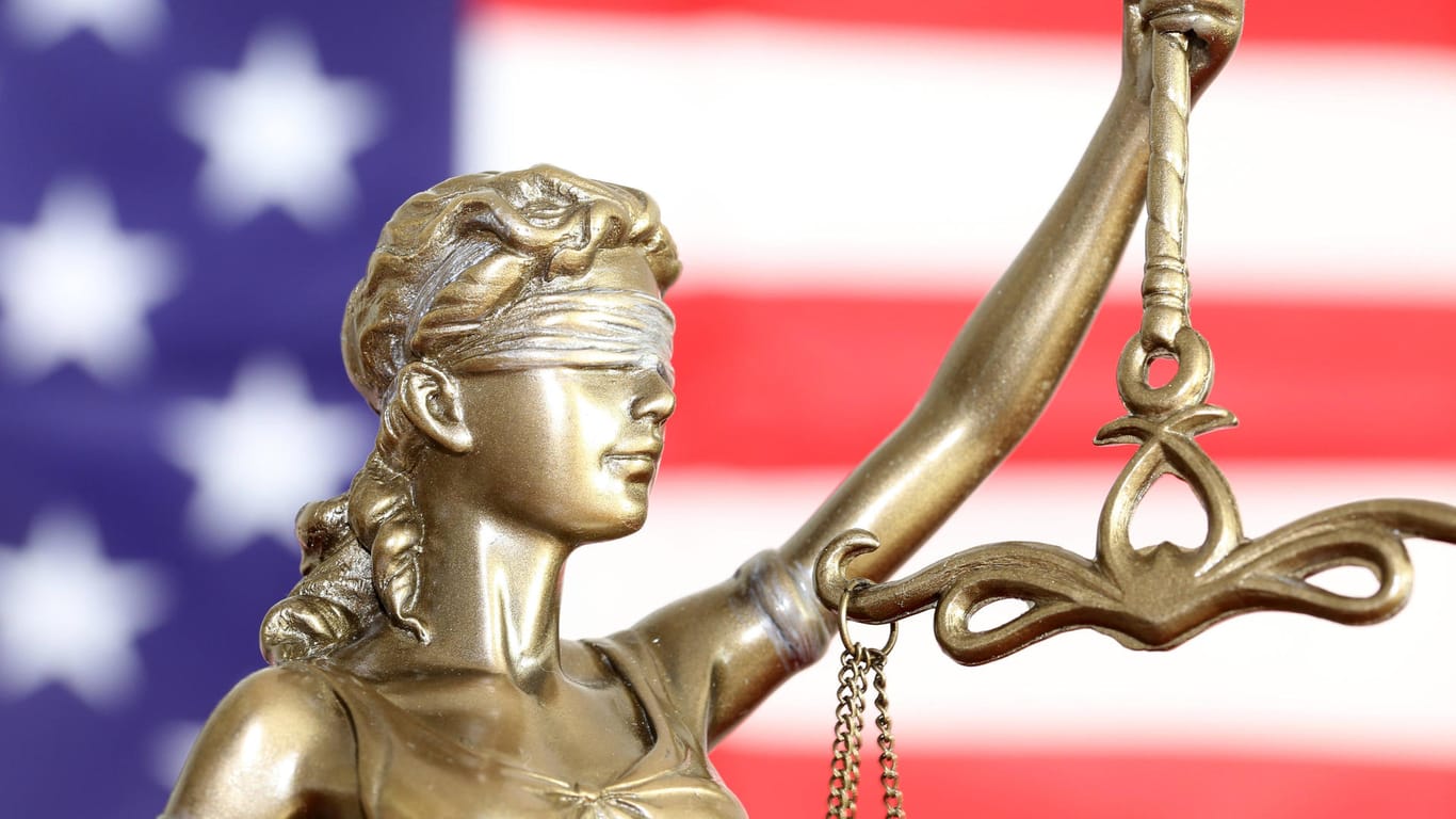 Justitia vor einer USA-Flagge (Symbolbild): Eine Hinrichtung in Texas wurde wegen Verletzung der Religionsfreiheit ausgesetzt.