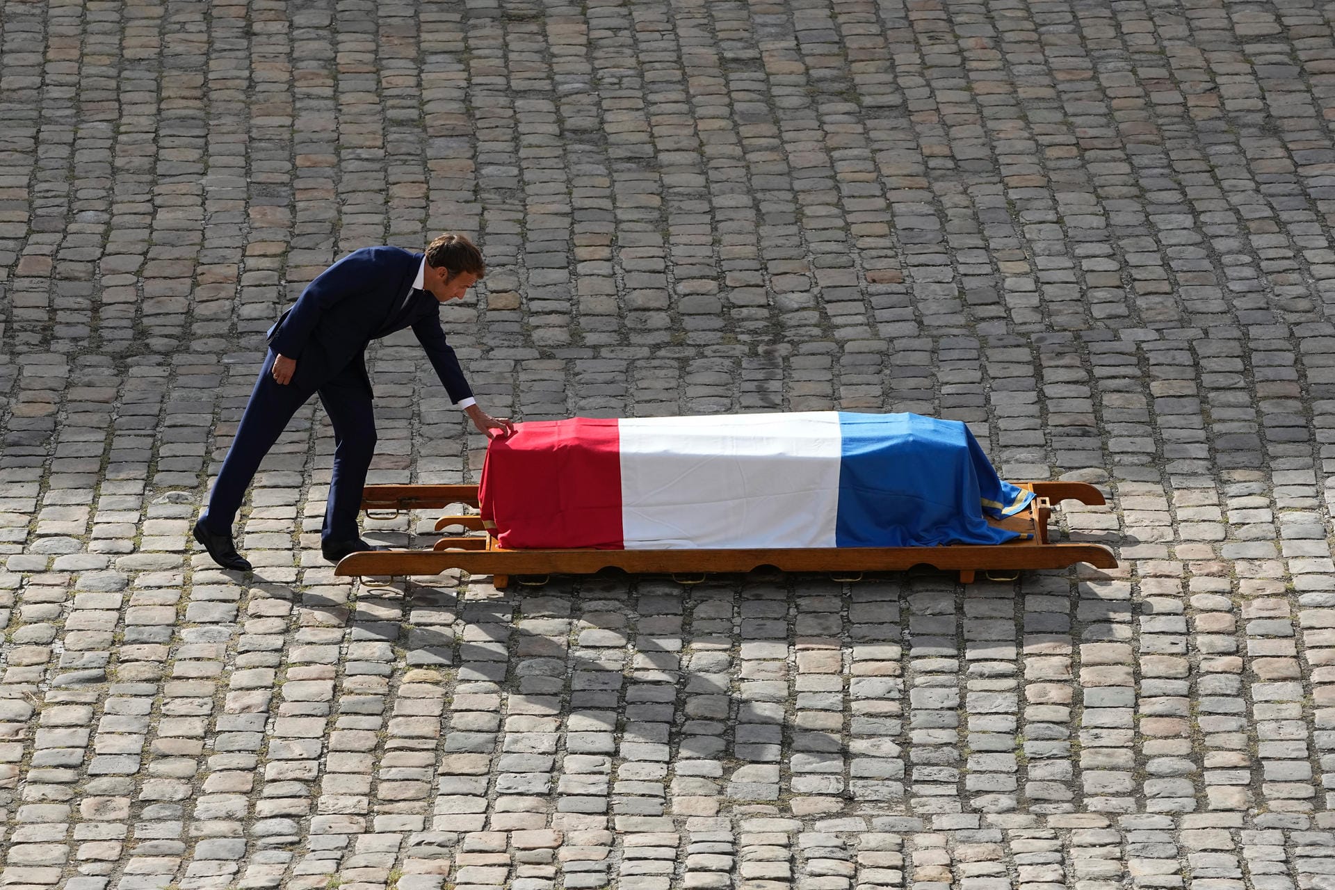 Emmanuel Macron berührt den Sarg des französischen Schauspielers Jean-Paul Belmondo, über dem die Trikolore liegt.