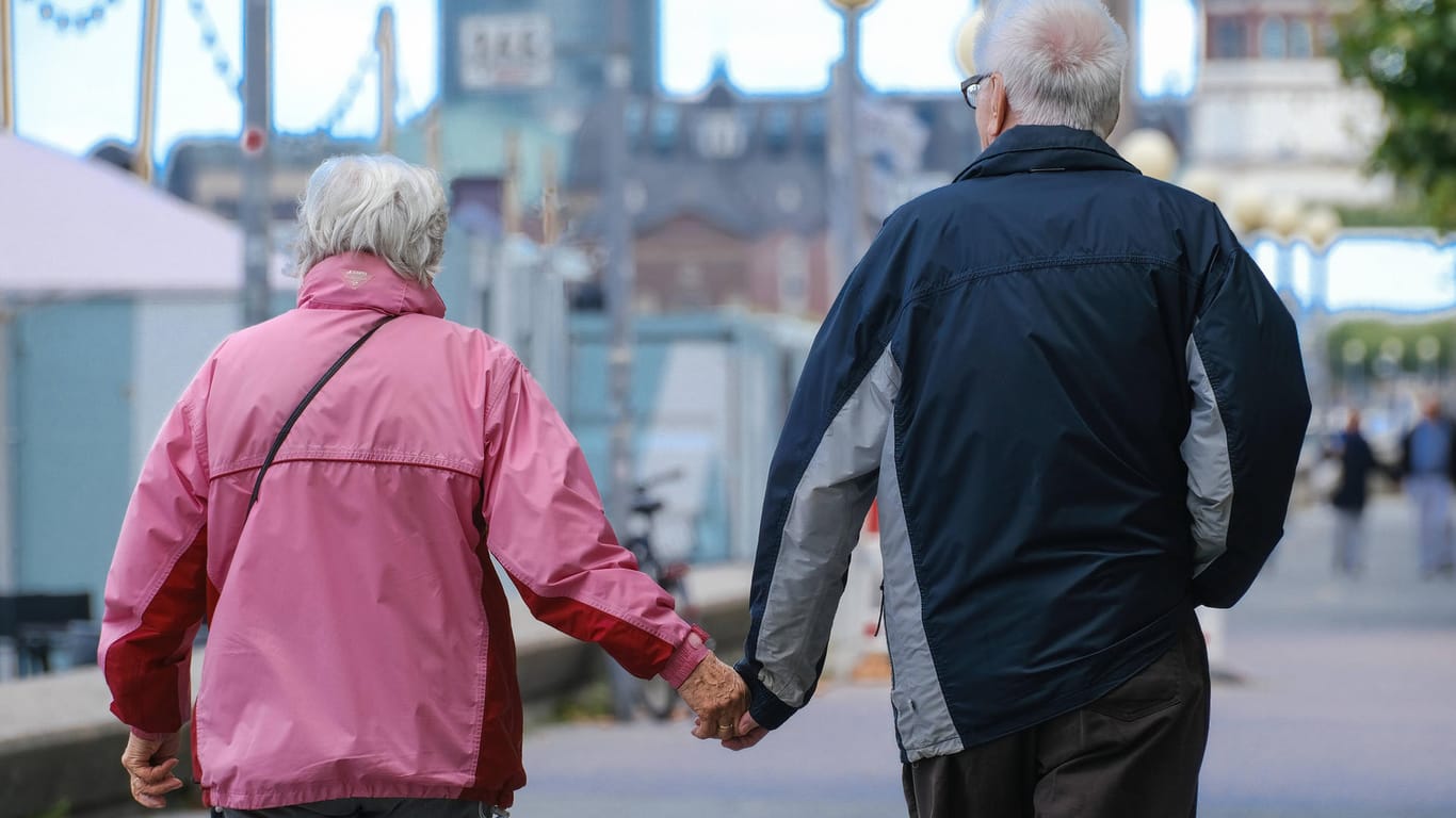 Ein älteres Ehepaar läuft Hände haltend durch Düsseldorf (Symbolbild). Für die Rentner in Deutschland könnte es 2022 mehr Geld geben.
