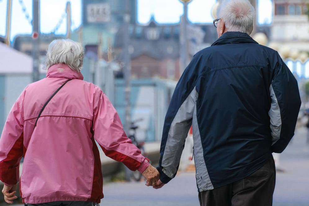 Ein älteres Ehepaar läuft Hände haltend durch Düsseldorf (Symbolbild). Für die Rentner in Deutschland könnte es 2022 mehr Geld geben.