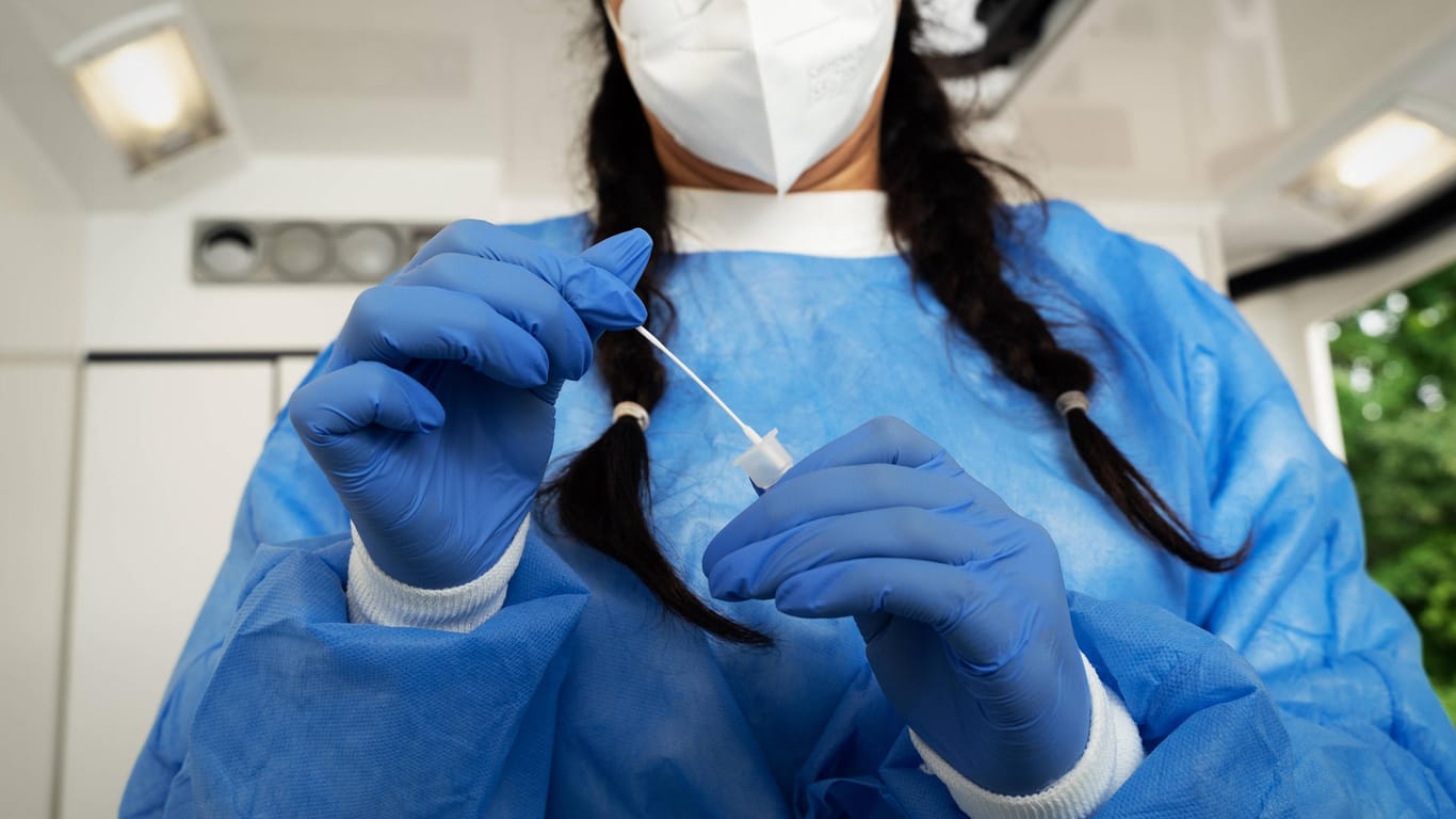 Eine Laborantin hält einen Teststab in der Hand (Symbolbild). Das RKI registrierte am Sonntag über 7.300 Neuinfektionen.