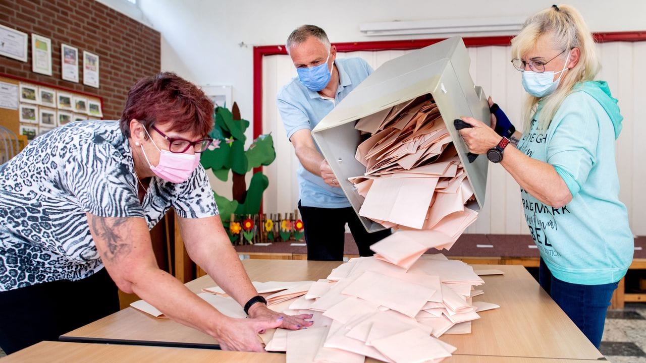 Wahlhelferinnen und ein Wahlhelfer entleeren im niedersächsischen Delmenhorst eine Wahlurne mit Stimmzetteln.
