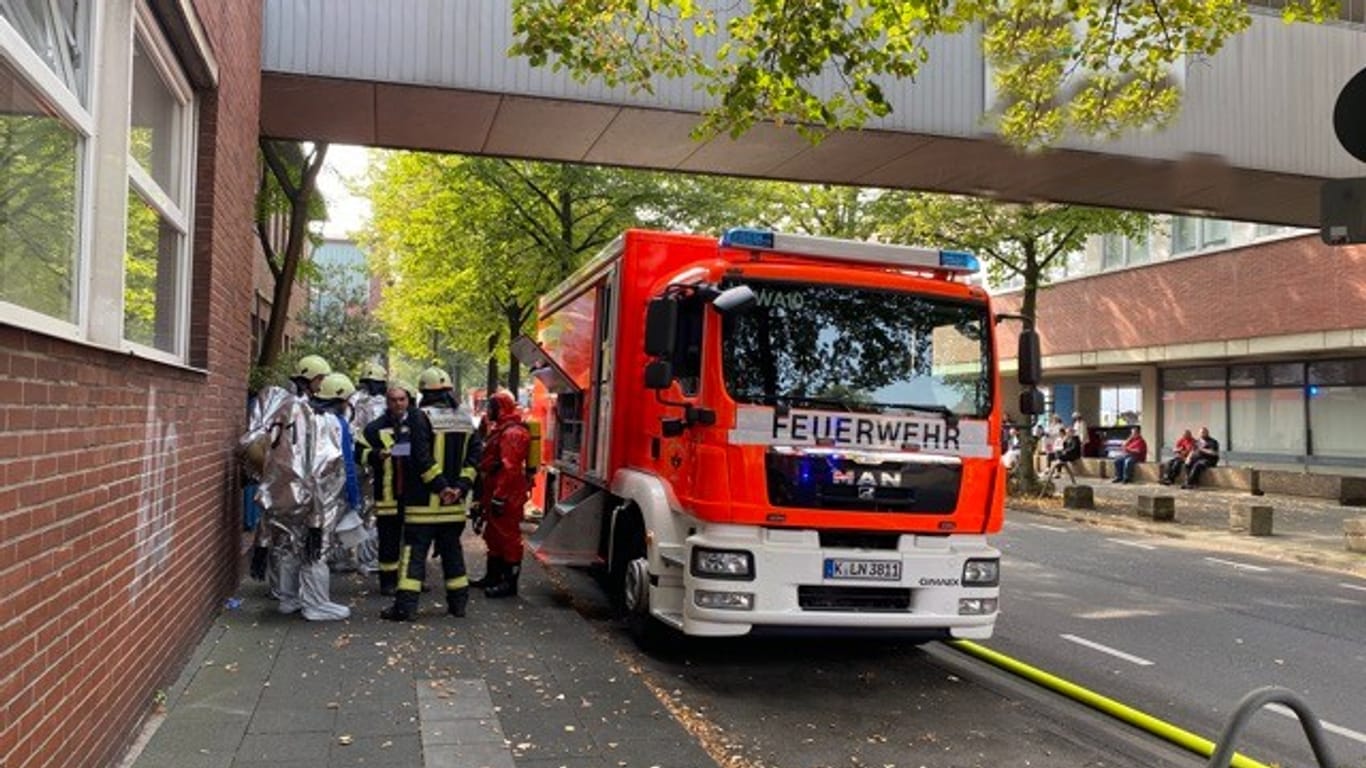 Feuerwehrleute stehen in Köln auf einer Straße: Dort untersuchen die Einsatzkräfte derzeit, woher ein auffälliger Geruch kommt.