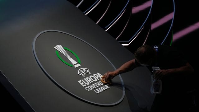 Ein Mitarbeiter reinigt das Logo der UEFA Europa Conference League.