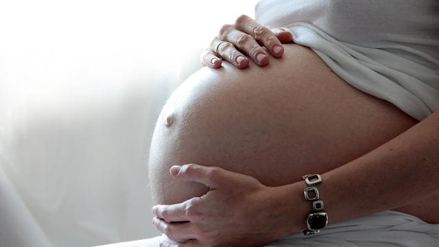 Eine Frau hält ihren schwangeren Bauch