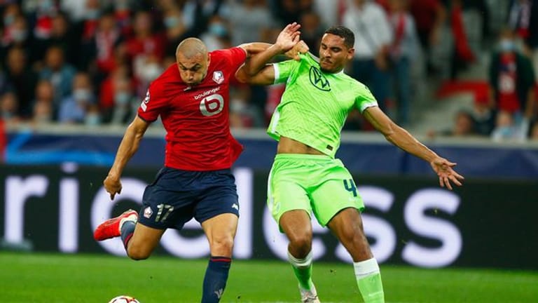 Maxence Lacroix vom VfL Wolfsburg (r) kann sich im Kampf um den Ball nicht gegen Burak Yilmaz vom OSC Lille durchsetzen.