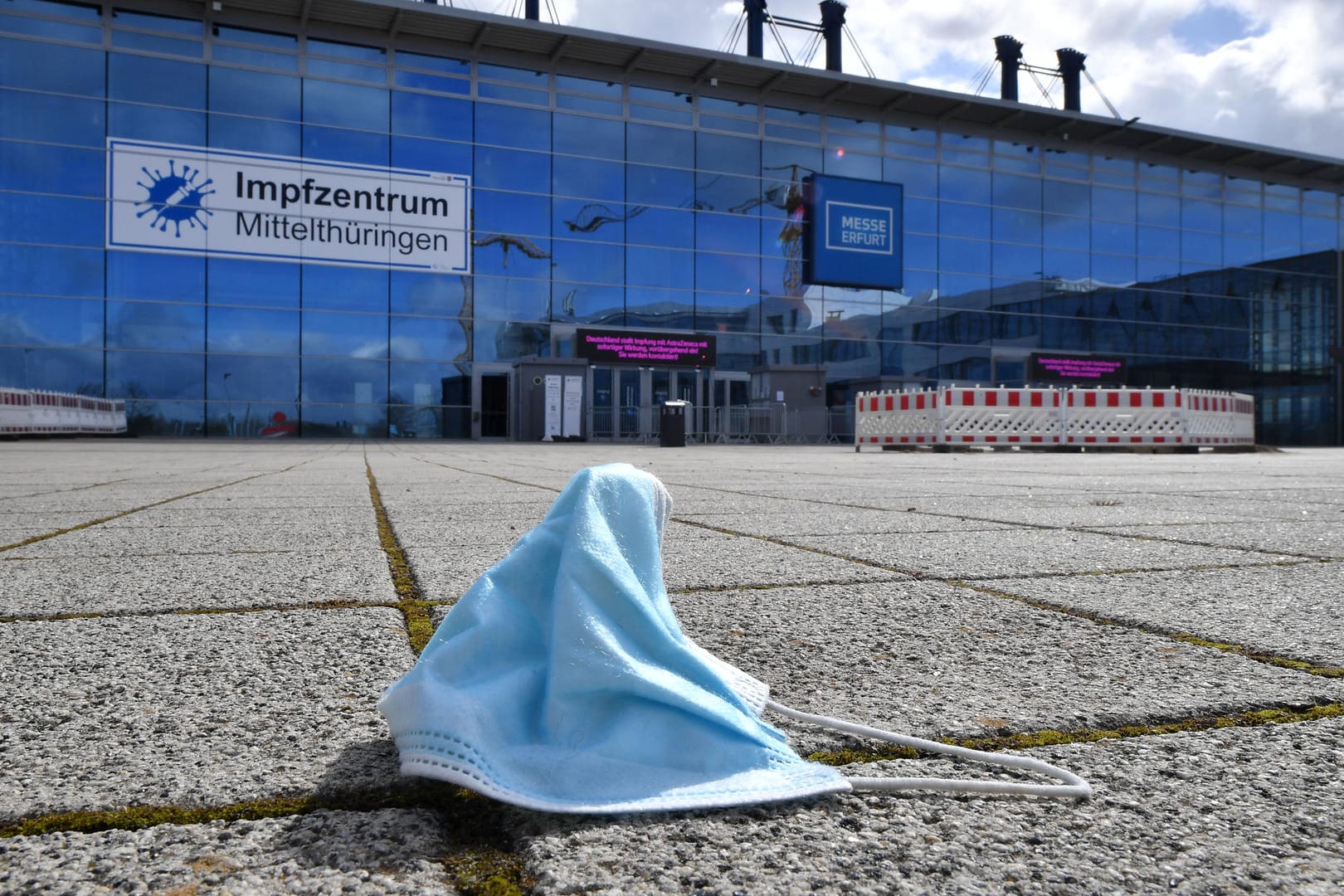 Eine Maske liegt vor dem Impfzentrum in der Messe Erfurt: Der bundesweite Inzidenzwert sinkt derzeit wieder.